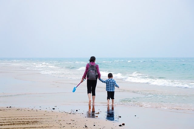 Madre e hijo caminado por la playa